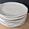 set of four white porcelain dinner plates with an uneven rustic shape and beaded edging