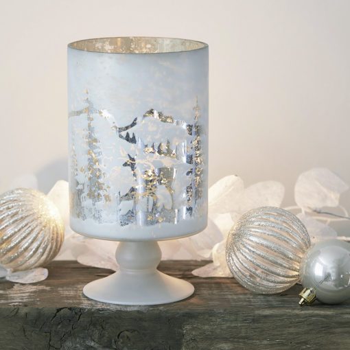 stemmed glass candle holder with a mottled white ocvering and cut-out winter design