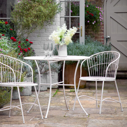 outdoor metal bistro set comprising of two chairs with elegantly curved backs and a round table finished in a distressed ivory