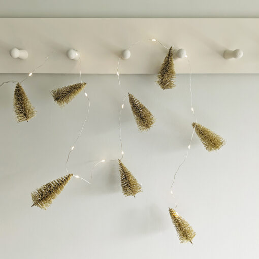 wire warm-white LED light garland interspersed with gold brush trees dusted in gold glitter