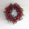 large faux christmas wreath with a sturdy round twig base adorned with mixed foliage stems and bursting with red berries