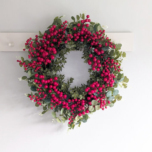 large faux christmas wreath with a sturdy round twig base adorned with mixed foliage stems and bursting with red berries