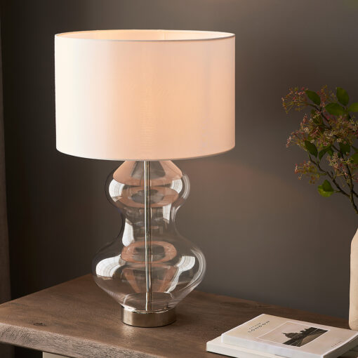 large glass table lamp with a clear hourglass silouette, silver nickel accents and vintage white drum lampshade