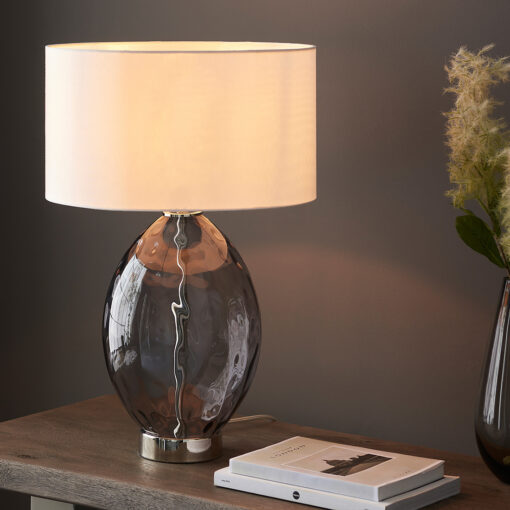 large oval glass table lamp with a textured dimple smoked grey glass base, silver nickel accents and a natural drum lampshade