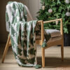 cosy green and cream knitted throw with a bold christmas tree pattern and green tassels