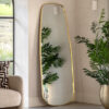 full length mirror with fluid curved edging and a slim metal frame finished in a warming gold