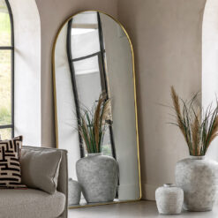 large oversized arched leaner mirror with a slim metal gold frame